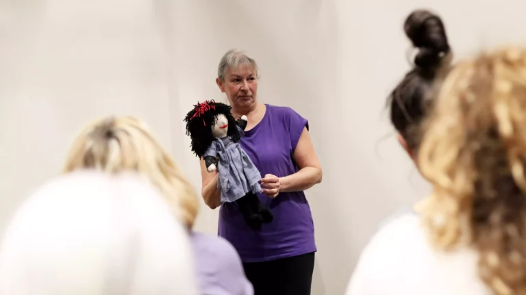 A middle-aged lady holding a plush doll and sharing the story of her treasured possession