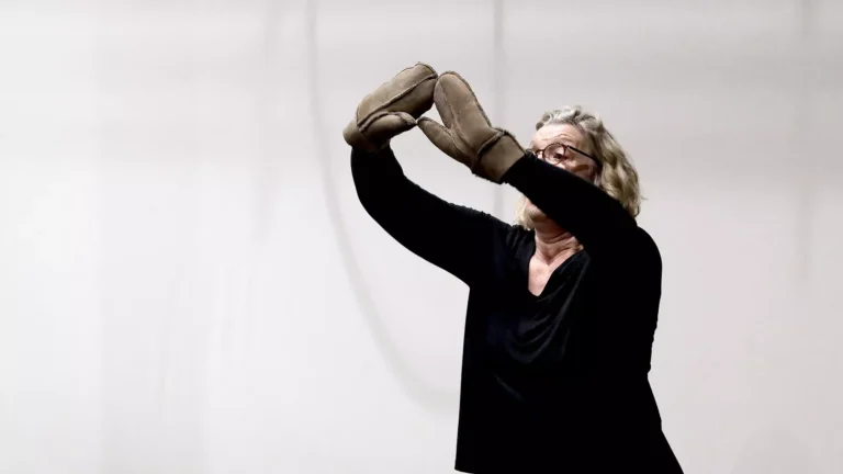A middle-aged lady dancing with a pair of mittens on